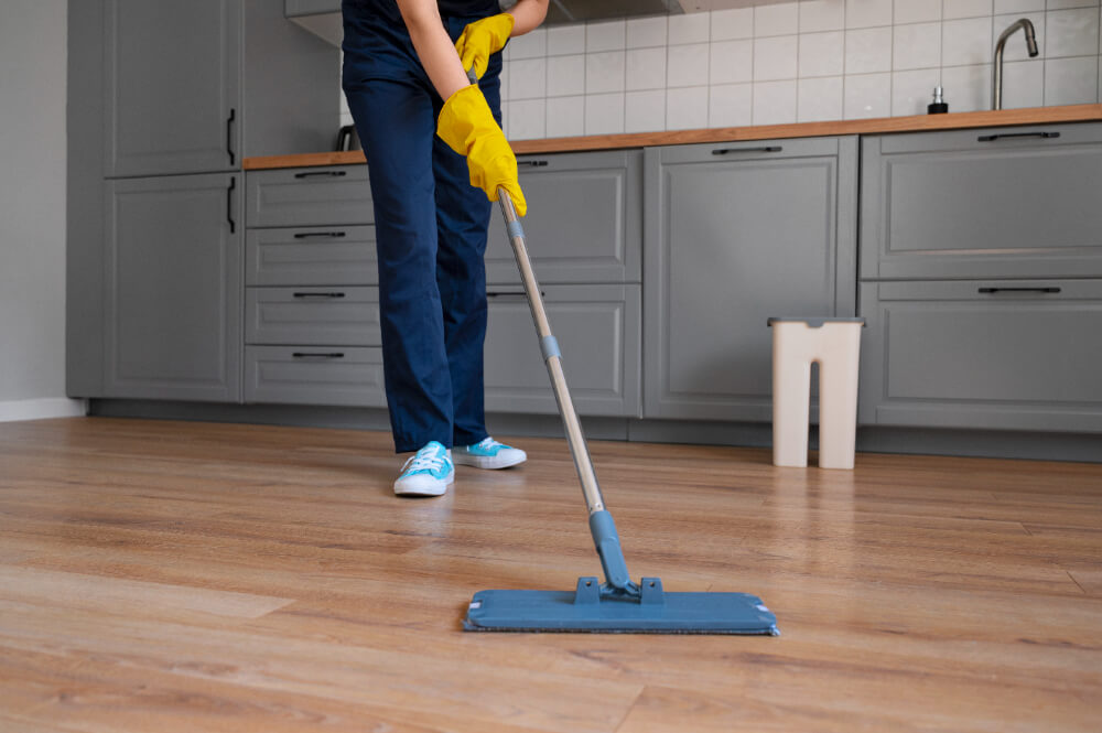 person cleaning kitchen vinyl planks floor with a mop